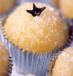 Foto da receita: Beijinho de Coco Tradicional - Leite condensado cozido com coco, modelado em bolinhas e passado em coco ralado. Cravo no topo. Festa de aniversário brasileira.