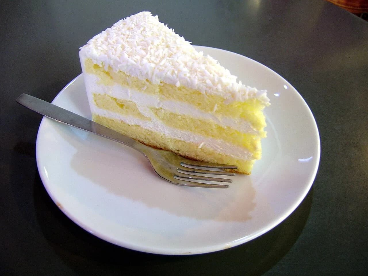 Foto da receita: Bolo Gelado de Coco (Toalha Felpuda) - Bolo branco embebido em calda de leite de coco, coberto com coco ralado e servido gelado em quadradinhos embrulhados em papel-alumínio.