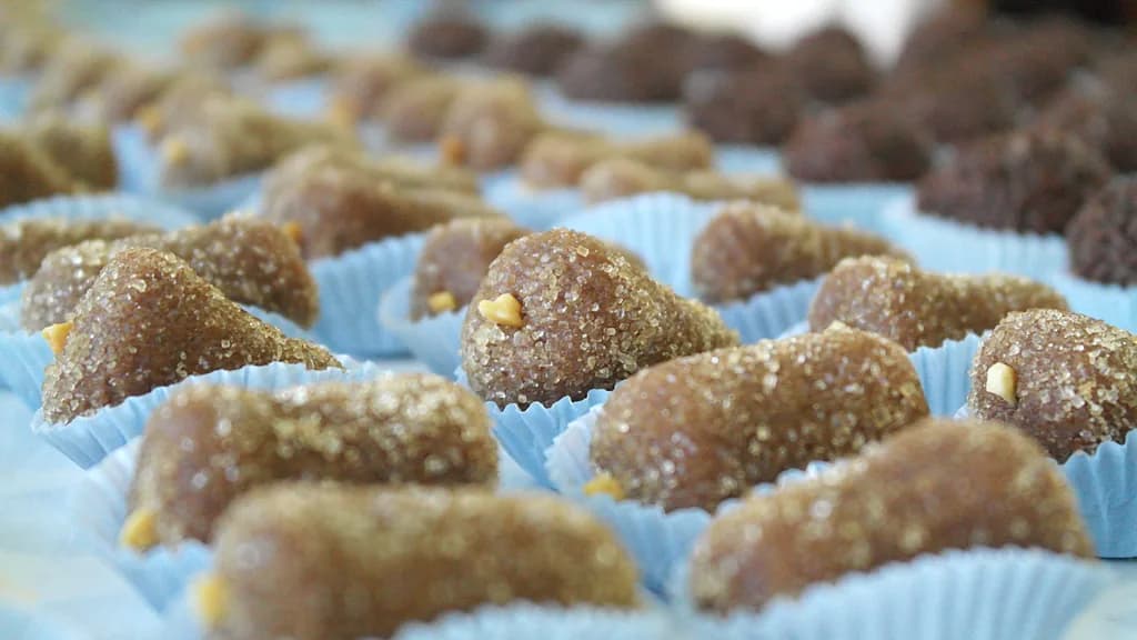 Foto da receita: Cajuzinho de Amendoim - Docinho de festa feito com amendoim torrado moído, leite condensado e chocolate, modelado em formato de caju e finalizado com um amendoim no topo.