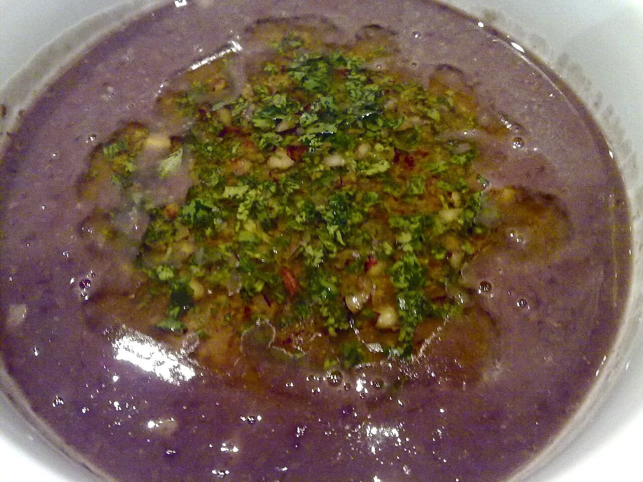 Foto da receita: Caldinho de Feijão - Feijão batido com o caldo, bacon, calabresa e temperos até virar um creme liso, servido em copinhos com couve crocante e torresmo. O petisco de boteco e de festa junina.