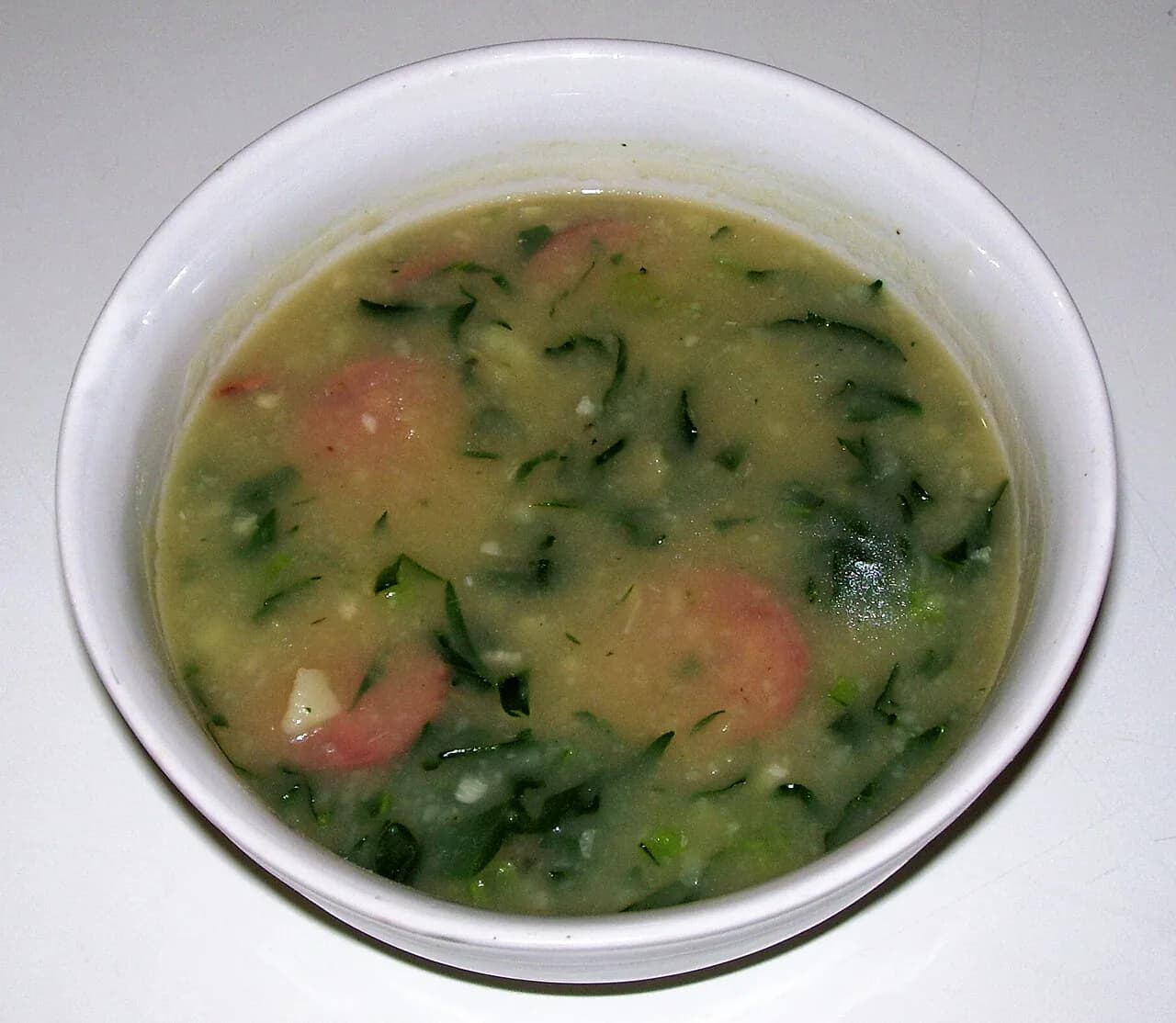 Foto da receita: Caldo Verde - Sopa portuguesa de batata cremosa com couve fatiada fina e rodelas de linguiça calabresa ou paio. A sopa de inverno e de festa junina mais amada do Brasil.