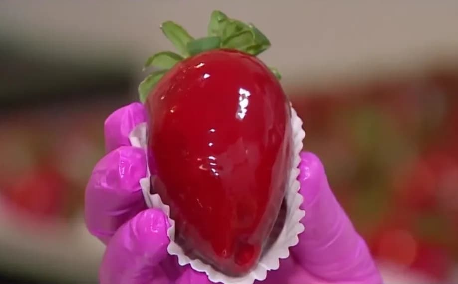 Foto da receita: Morango do Amor com Brigadeiro Branco - O doce que tomou conta das redes: morango envolto em brigadeiro branco e coberto por uma casquinha de caramelo vermelho que quebra ao morder.