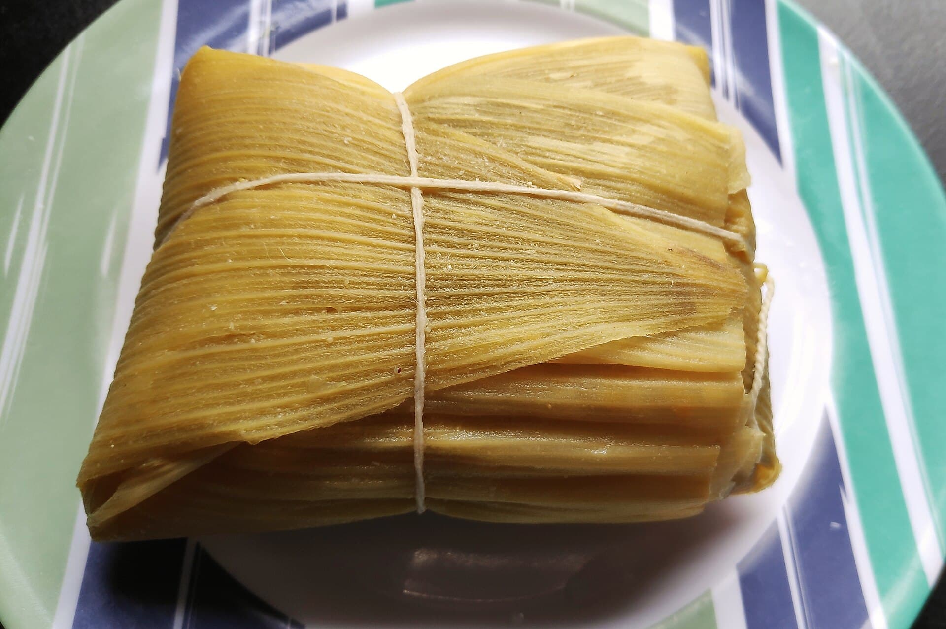 Foto da receita: Pamonha Doce na Folha de Milho - Massa de milho verde com leite e açúcar, embrulhada em palha de milho e cozida na água. Verão de festa junina.