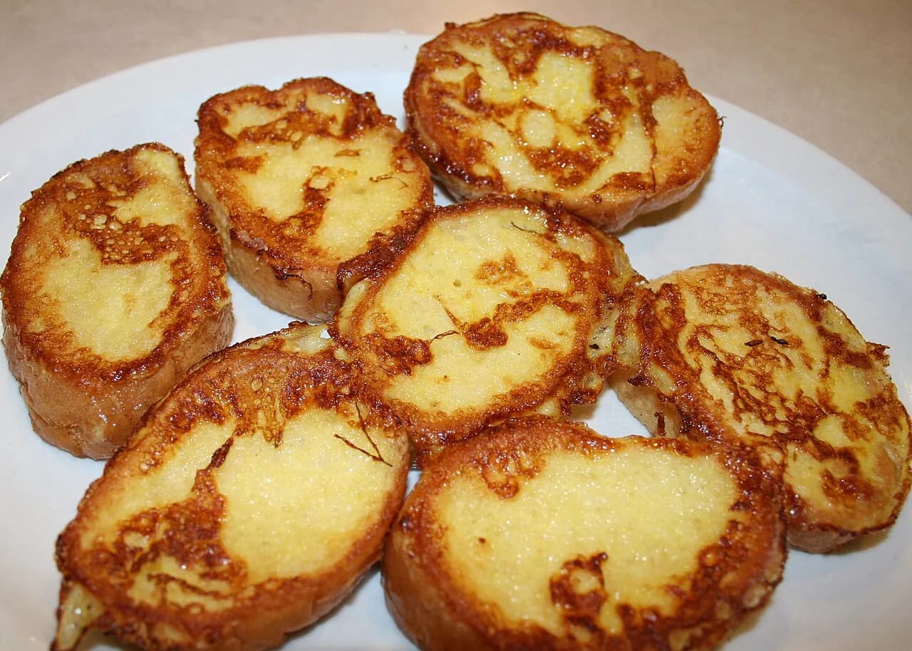Foto da receita: Rabanada Tradicional de Natal - Fatias de pão amanhecido embebidas em leite com açúcar, passadas no ovo, fritas e polvilhadas com açúcar e canela. Crocante por fora e cremosa por dentro.