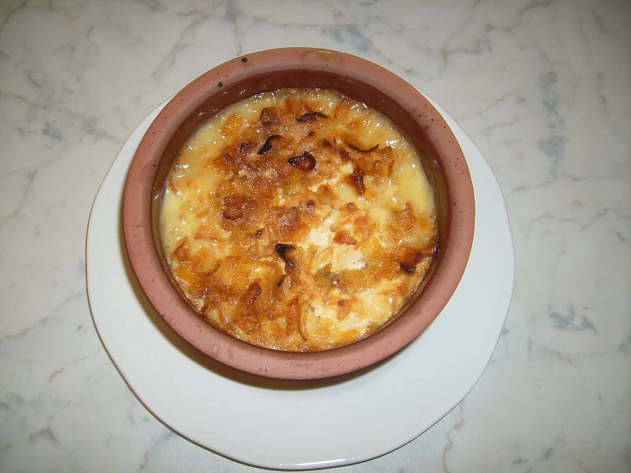 Foto da receita: Arroz de Forno Cremoso - Arroz cozido misturado com frango ou presunto, milho, ervilha e molho branco, coberto com muçarela e gratinado. A melhor forma de aproveitar o arroz de ontem.
