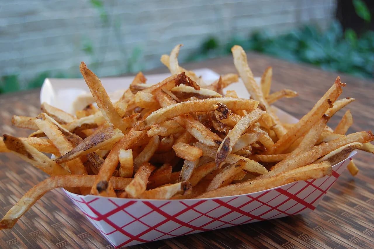 Foto da receita: Batata Frita Crocante na Air Fryer - Batata frita sequinha e dourada com uma colher de óleo. O truque está no molho em água fria e na secagem antes de ir para a cesta.