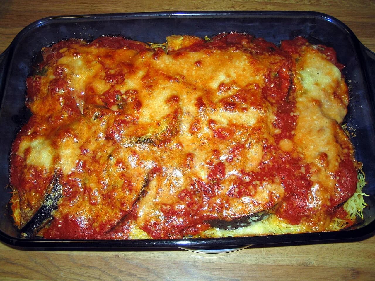 Foto da receita: Berinjela à Parmegiana - Fatias de berinjela empanadas e douradas, montadas em camadas com molho de tomate, muçarela e parmesão, e gratinadas. A parmegiana vegetariana que vale por um prato principal.