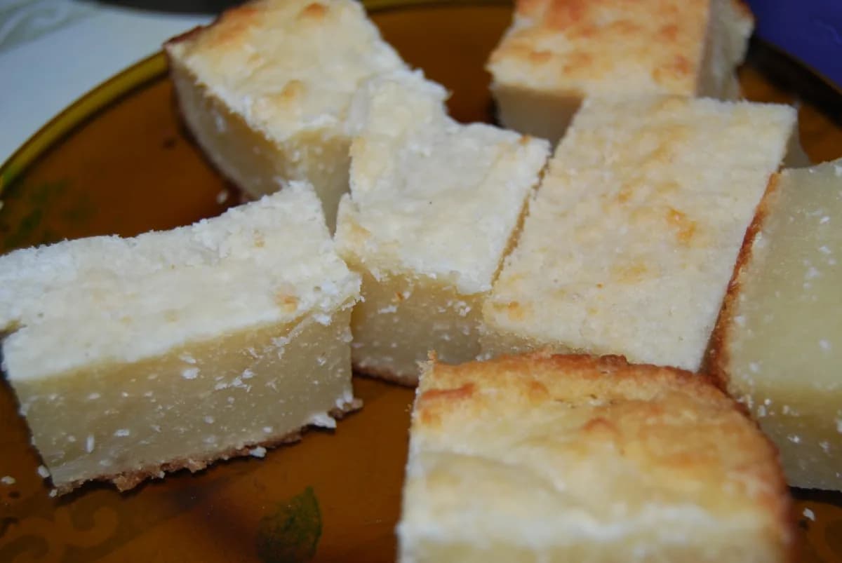 Foto da receita: Bolo de Aipim (Mandioca) Cremoso - Bolo de mandioca crua ralada com coco e leite de coco, que assa com uma camada cremosa embaixo e casquinha dourada em cima. Sem farinha de trigo.