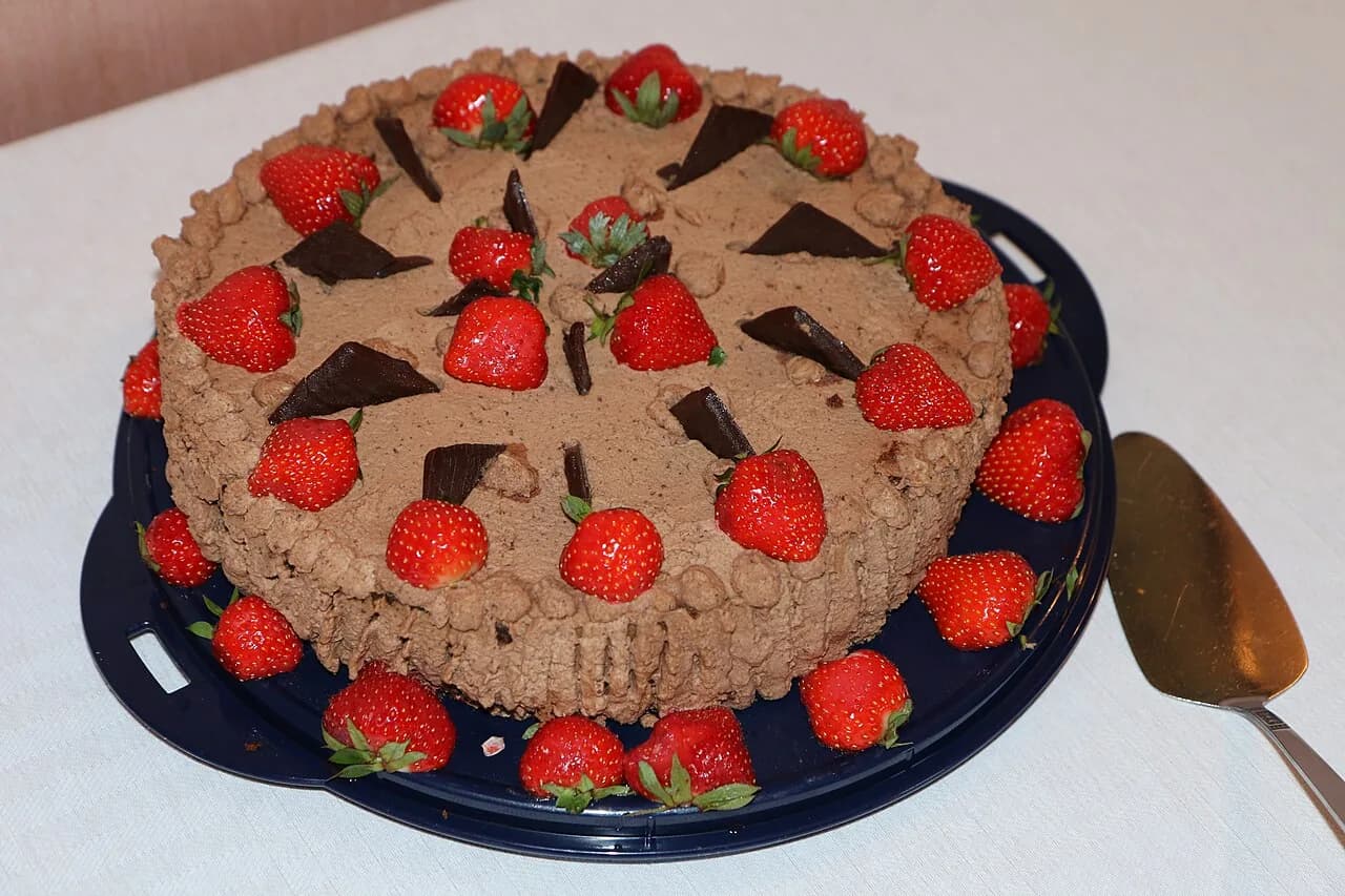 Foto da receita: Bolo de Aniversário com Brigadeiro Branco e Morango - Pão de ló molhado com calda, recheado com brigadeiro branco cremoso e morangos frescos, coberto com chantilly. O bolo de festa que agrada todo mundo.