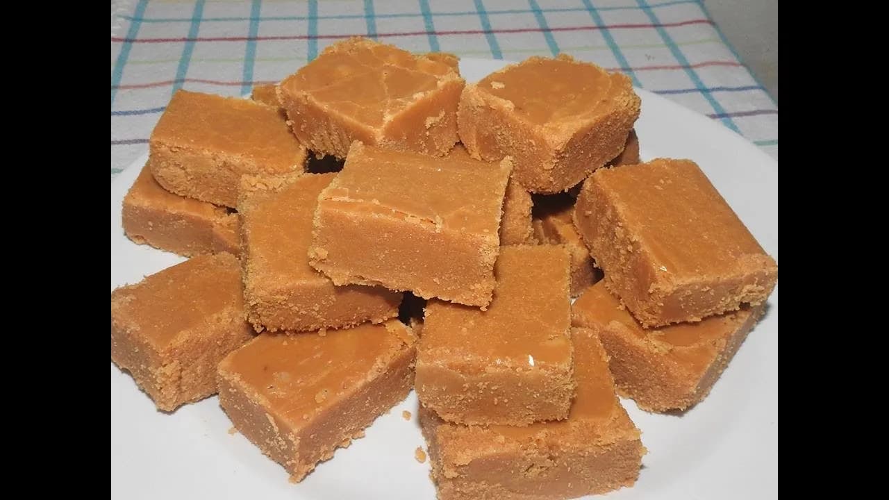 Foto da receita: Doce de Leite Cortado em Pedaços - Leite, açúcar e canela cozidos lentamente até virar uma massa firme, cortada em quadradinhos. Doce de tabuleiro de fazenda.