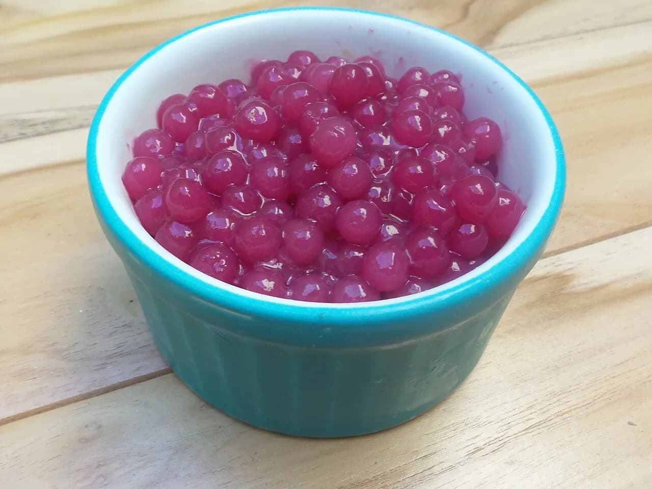 Foto da receita: Sagu de Vinho com Creme de Baunilha - Bolinhas de sagu cozidas em vinho tinto com açúcar e cravo, servidas geladas com um creme de baunilha por cima. Sobremesa tradicional do Sul do Brasil.